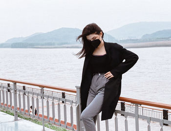 Woman standing by railing against lake