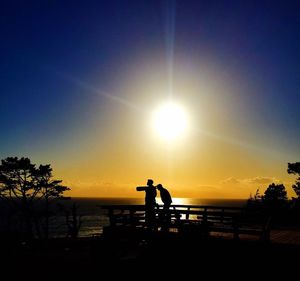 Silhouette man standing by sea against clear sky during sunset