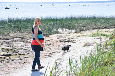 Full length portrait of pregnant woman with dog walking on land
