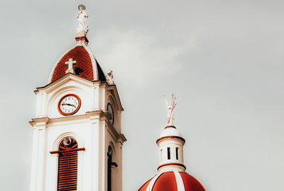 Low angle view of clock tower amidst buildings against sky