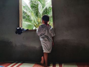 Rear view of boy standing against wall