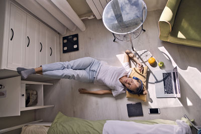 Young woman lying at the window at home with laptop