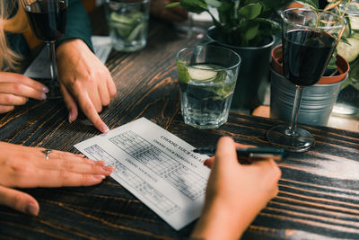 Cropped hands writing on paper at table in restaurant