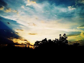 Silhouette of trees against cloudy sky