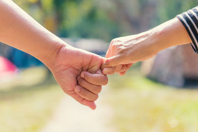 Close-up of friends taking pinky promise outdoors