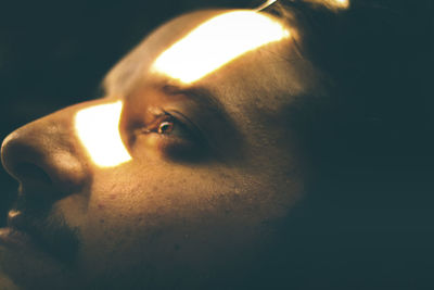 Close-up of young man face looking away in darkroom