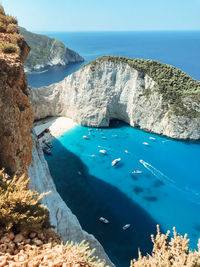 High angle view of rocks by sea against blue sky