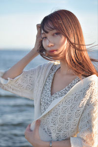 Young woman at beach against sky