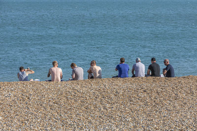 Rear view of people sitting on beach