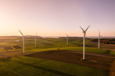 Windmills on field against sky during sunset