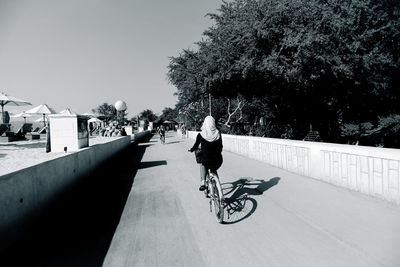 Rear view of man riding bicycle against clear sky