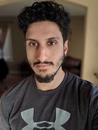 Close-up portrait of young man with beard at home