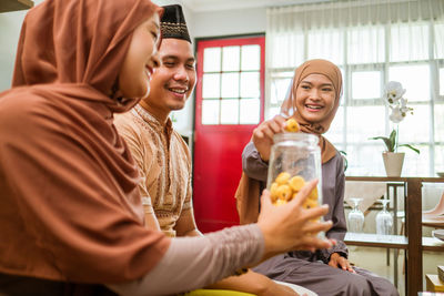 Woman holding sweet from jar at home