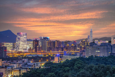 Modern buildings in city against sky during sunset