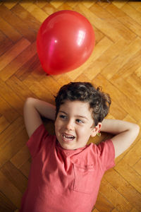 High angle portrait of smiling boy on hardwood floor