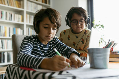 Boy looking away while sitting on table