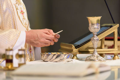 Priest with metal containers at table in church