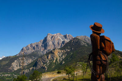 Rear view of person looking at mountains against clear blue sky