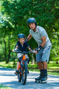 Grandfather teaching grandson to ride bicycle on road