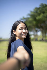 Portrait of smiling young woman standing in park