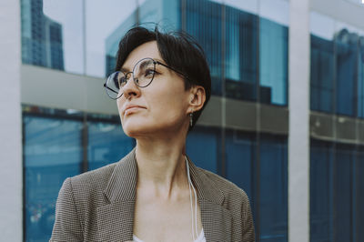 Contemplating businesswoman in front of office building