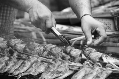 Midsection of man holding fish on barbecue grill