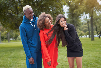 Smiling friends standing in park