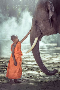 Full length of boy standing by elephant on field