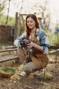 Smiling woman with hen at farm