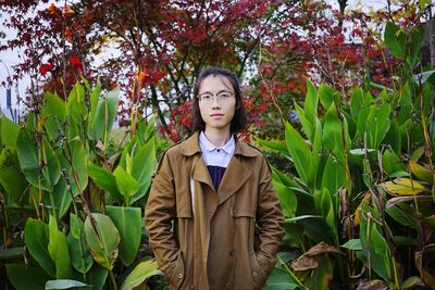 Portrait of young woman standing by plants