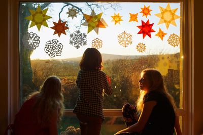 Siblings sitting against window glass