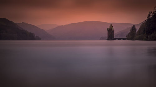 Scenic view of lake vyrnwy by mountains during sunset