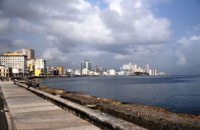 Sea by buildings in city against sky