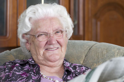 Portrait of smiling senior woman sitting on chair at home