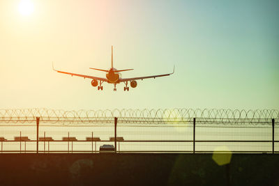 Low angle view of airplane flying against sky during sunset