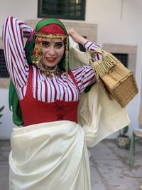 Portrait of young woman wearing traditional clothing while standing against wall