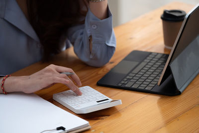 Midsection of woman using laptop on table