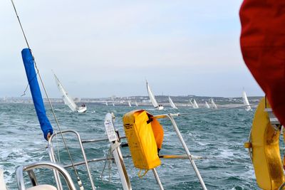 Close-up of yellow sailing ship in sea against sky