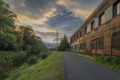 Road amidst trees against sky during sunset