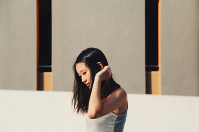 Close-up of beautiful young woman against building