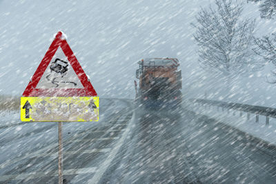 Road sign warns of ice and snow at winter