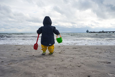 Rear view of woman on beach against sky