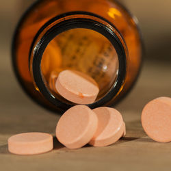 Close-up of orange medicines spilling from bottle on table