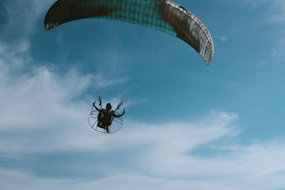 Low angle view of person paragliding against sky