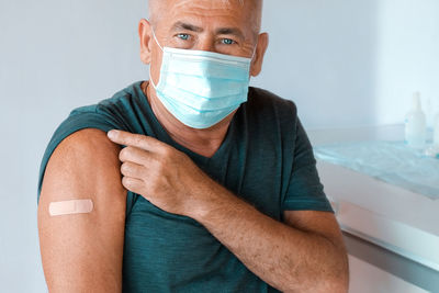 Senior man is after covid-19 vaccine. old man showing arm with bandage, patch  coronavirus vaccine