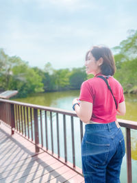 Woman looking away while standing on railing
