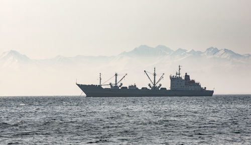 Large fishing vessel on the background of hills and volcanoes