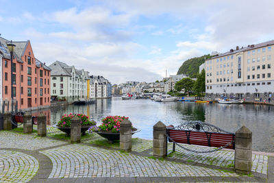 Buildings by river against sky in city