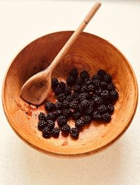 Blackberries and  wooden spoon in a grained wooden bowl. foraged, locally sourced, nutritious fruit.