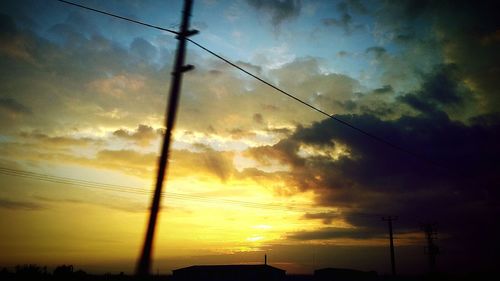 Low angle view of electricity pylon against cloudy sky